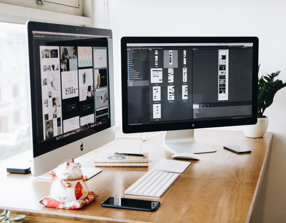 A design workspace with two monitors showing page layouts